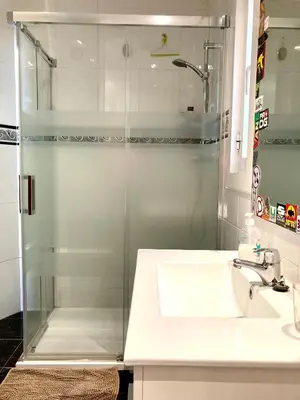 a bathroom with a glass shower and a sink at Rio Turia Skatehouse in Valencia