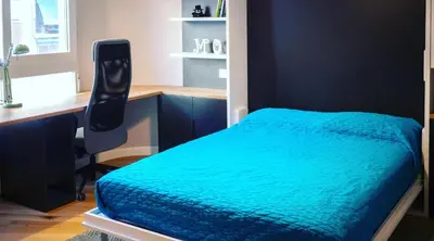 a bedroom with a bed with a desk and a blue blanket at Hexagonal Design Apartment in Valencia