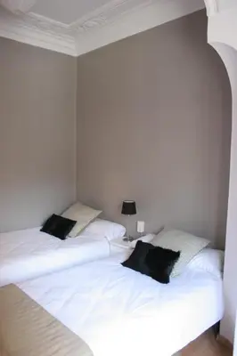 two beds in a room with white sheets and black pillows at 7 Moons B&B in Valencia