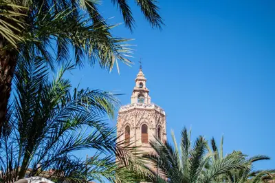 a tall tower with a steeple with palm trees at Catedral Apartments in Valencia