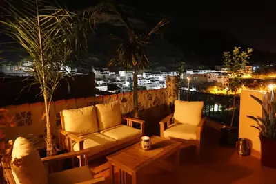 a balcony with couches and a table and a city at CASA DEL ARTE casa rural in Chulilla