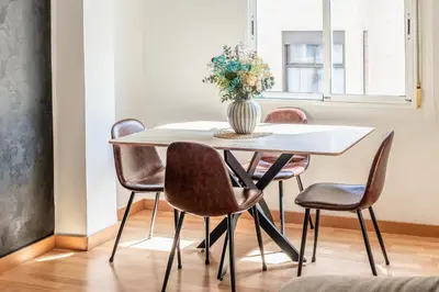 a dining room table with chairs and a vase with flowers at Casa los Buhos in Valencia