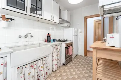 a white kitchen with a sink and a stove at Casa los Buhos in Valencia
