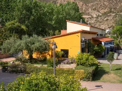 a yellow and white house with a mountain in the background at El Cerrao-PauNatura in Sot de Chera