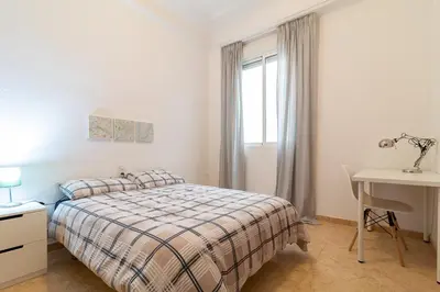 a bedroom with a bed and a desk and a window at La Casa de los Espejos in Valencia