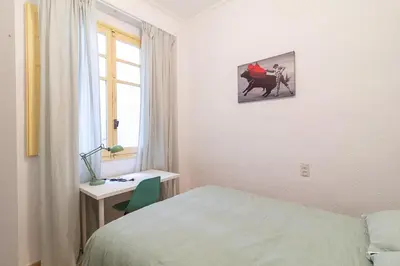 a room with a bed and a desk and a window at La Casa de los Espejos in Valencia