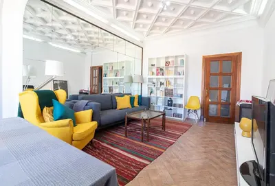 a living room with a blue couch and yellow chairs at La Casa de los Espejos in Valencia