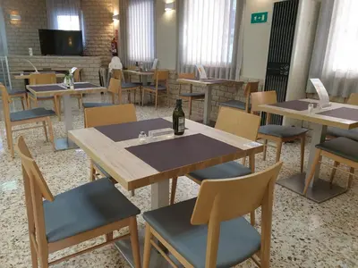 a dining room with tables and chairs and a bottle of wine at Hostal Moreno in Silla