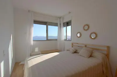a white bedroom with a bed and a large window at Can Lou-Casa con Caracter en Cullera in Faro de Cullera