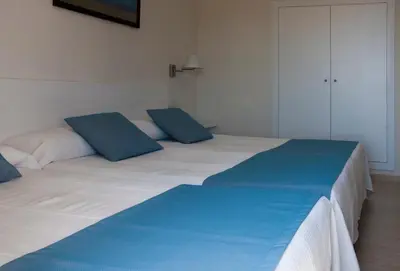 a large bed with blue pillows on top of it at Hotel Sicania in Cullera