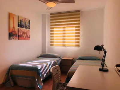 a room with two beds and a table and a window at Apartamento en Universidad y cerca de la playa in Valencia