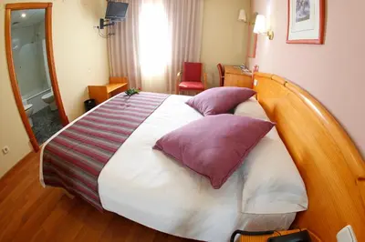 a bedroom with a large bed with purple and white pillows at Maria de Luna in Segorbe