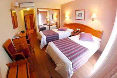 a hotel room with two beds and a mirror at Maria de Luna in Segorbe