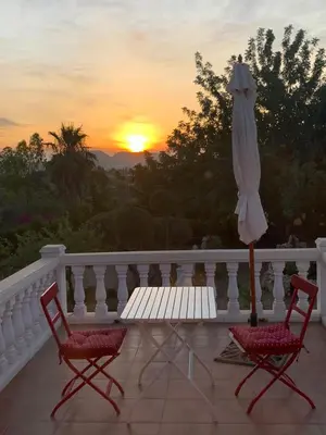 two chairs and an umbrella on a balcony with the sunset at CASA MARTINEZ MONTROY à 3 kms de MONTSERRAT VALENCIA in Montroy