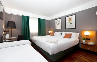 two beds in a hotel room with green curtains at Hotel Malcom and Barret in Valencia