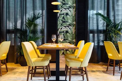 a dining room with a table and yellow chairs at Hotel Malcom and Barret in Valencia