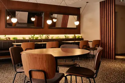 a dining room with tables and chairs and a mirror at Room Mate Cosmo - City Centre, Valencia in Valencia