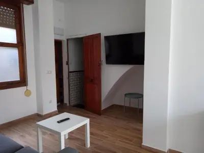 a living room with a table and a tv on a wall at Sofia's Flat in Valencia