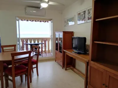 a living room with a dining room table and a television at IDEALLY located on BEACH in Port Saplaya