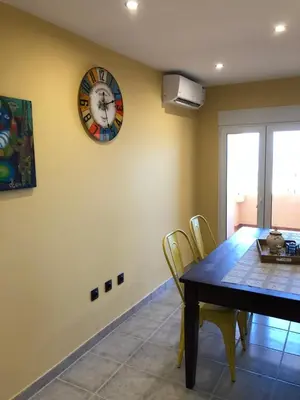 a dining room with a table and a clock on the wall at Sea view Port Saplaya Apartments,2 in Port Saplaya