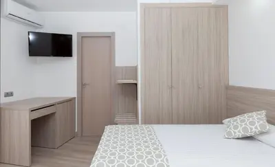 a bedroom with a bed and a desk and a television at Hotel Olympia Ronda II in El Puig