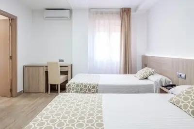 a hotel room with two beds and a desk at Hotel Olympia Ronda II in El Puig