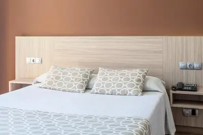 a bedroom with a large white bed with two pillows at Hotel Olympia Ronda II in El Puig