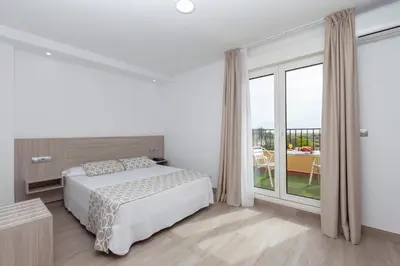 a white bedroom with a bed and a large window at Hotel Olympia Ronda II in El Puig