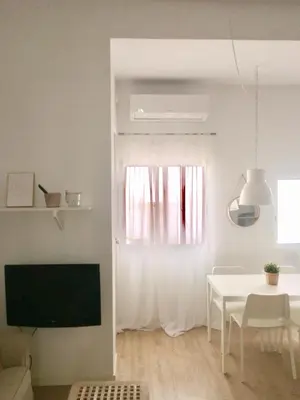 a white living room with a table and a television at Cozy apartment Valencia city center! in Valencia