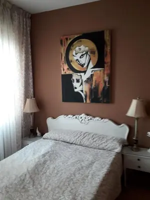 a bedroom with a white bed and a painting on the wall at Carrer Roma in Sagunto