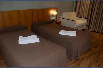 a hotel room with two beds and a chair at Hotel AS Torrent in Torrent