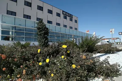 an office building with yellow flowers in front of it at Hotel AS Torrent in Torrent