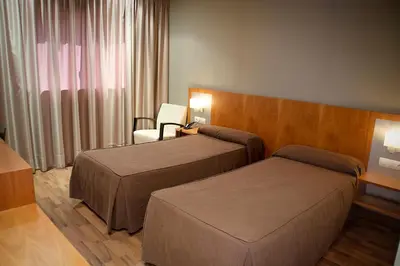 a hotel room with two beds and a chair at Hotel AS Torrent in Torrent