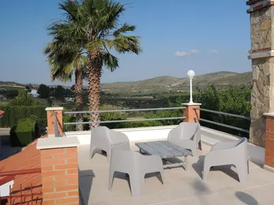 a patio with a table and chairs and a palm tree at Finca Mirador in Macastre
