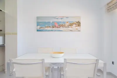 a white dining room table with chairs and a painting on the wall at Los Olivos Apartment Cullera in Cullera