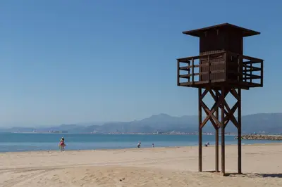a lifeguard tower on a beach with people in the water at Los Olivos Apartment Cullera in Cullera