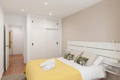 a white bedroom with a large bed with a yellow blanket at FLORIT FLATS - Apartment Torres de Quart I in Valencia
