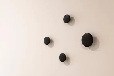 a group of black spheres on a white wall at Blanq Comedias in Valencia