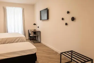 a room with two beds and a desk and a television at Blanq Comedias in Valencia
