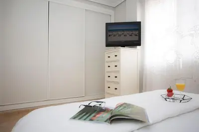 a bedroom with a bed with a tv and a book and glasses at SingularStays Puzol Beach VII in Puzol