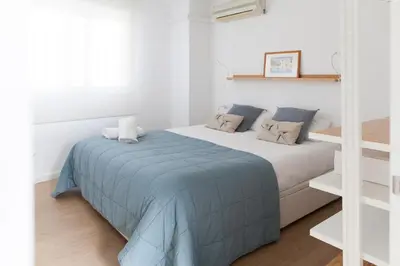 a white bedroom with a bed with a blue blanket at FLORIT FLATS - Apartment Torres de Quart II in Valencia