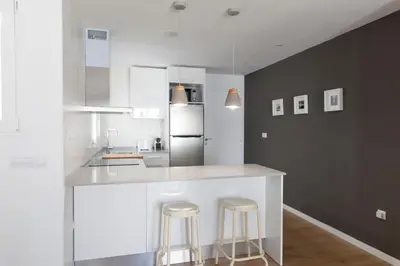 a white kitchen with two bar stools and a refrigerator at FLORIT FLATS - Apartment Torres de Quart II in Valencia