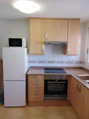 a kitchen with white appliances and wooden cabinets at El apartamento de Marina en Chilches playa in Xilxes