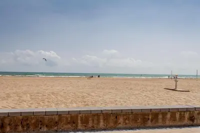 a beach with people and a kite in the distance at ApartUP Patacona Select in Valencia