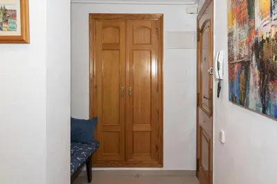 a hallway with a wooden door and a chair at Nueva Vista 2º-4 in Cullera