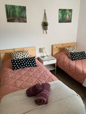 a bedroom with two beds with pink blankets and a table at Casa Valle del Turia in Chulilla