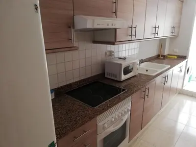 a small kitchen with a microwave and a sink at Parquemar VIII Solo Familias Serviplaya in Playa de Xeraco