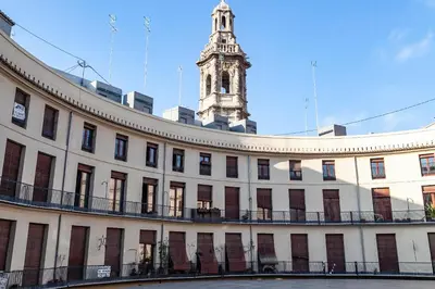a large white building with a clock tower in the background at Plaza Redonda Center in Valencia