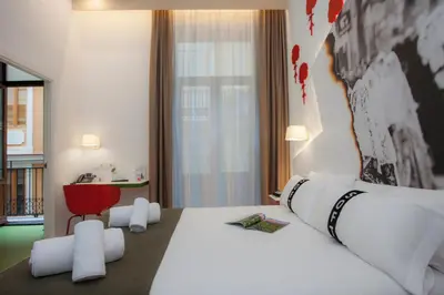 a hotel room with a large bed and a red chair at Casual Socarrat Valencia - Adults Only in Valencia