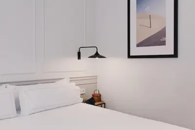 a white bed with white pillows and a black lamp at Room Mate Collection Helen Berger in Valencia